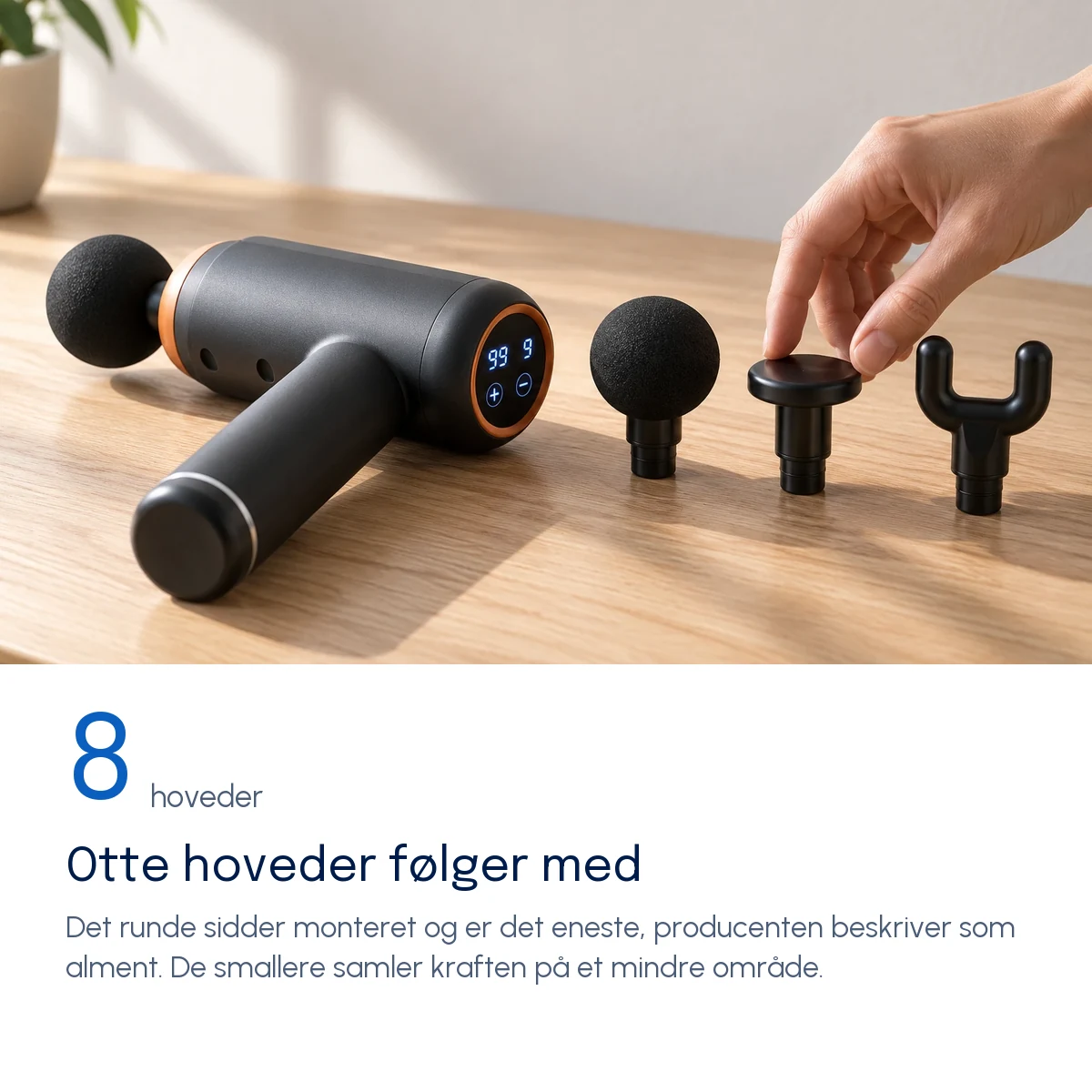 Otte hoveder følger med — Massagepistolen på et træbord med det runde hoved monteret og tre løse hoveder ved siden af
